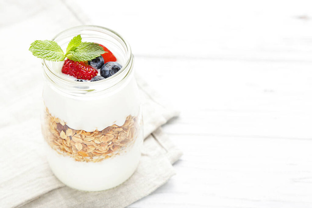 Tasty granola with cream and berries on white wooden background - Φωτογραφία, εικόνα