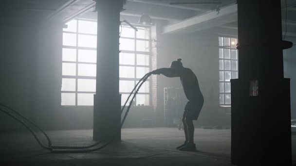 Een man die touwen vecht tijdens de training. Sportman die intensieve training uitvoert - Foto, afbeelding