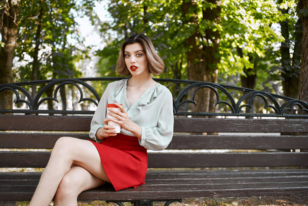 woman sitting in summer park with a cup of coffee outdoors - Photo, Image