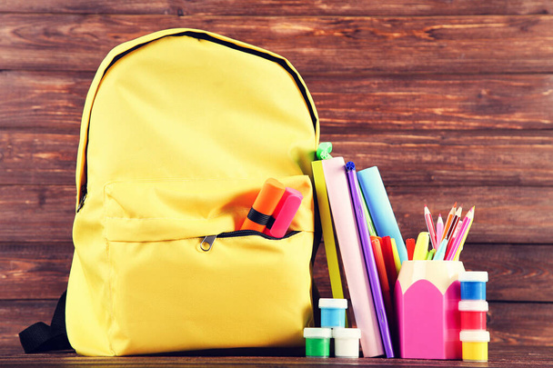 Backpack with school supplies on brown wooden background - Foto, Bild