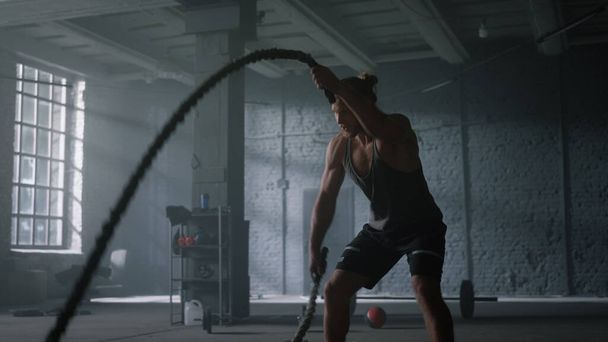 Человек тренируется с боевыми веревками в спортзале. Спортсмен делает интенсивные тренировки - Фото, изображение