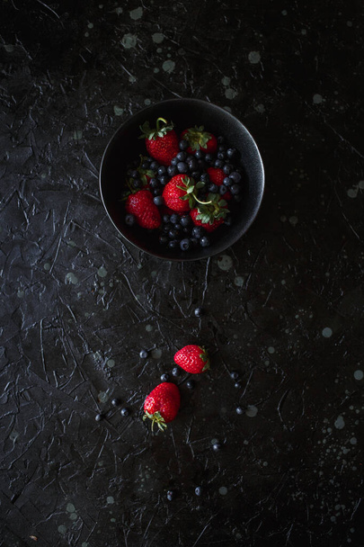strawberries and blueberries, food on a black background - 写真・画像
