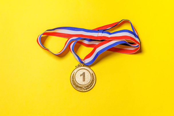 Simply flat lay design winner or champion gold trophy medal isolated on yellow colorful background. Victory first place of competition. Winning or success concept. Top view copy space. - Photo, Image
