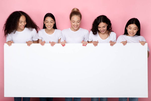ピンクの背景にテキストのためのホワイトボードを表示する5人の女性 - 写真・画像