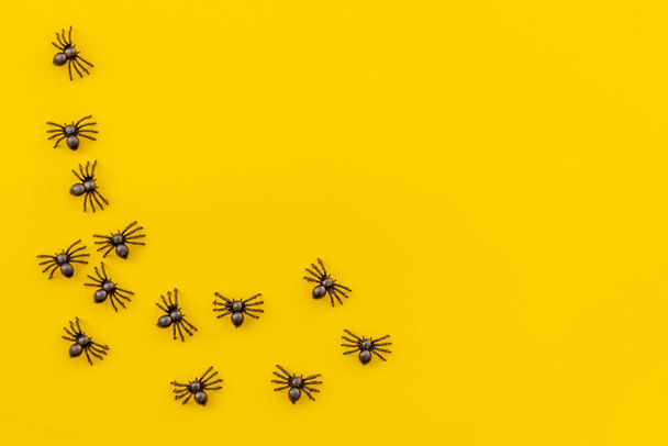 Halloween minimal decorations, composition with many black spiders isolated on yellow background. Halloween celebration trick or treat concept. Flat lay top view copy space Banner - Photo, Image