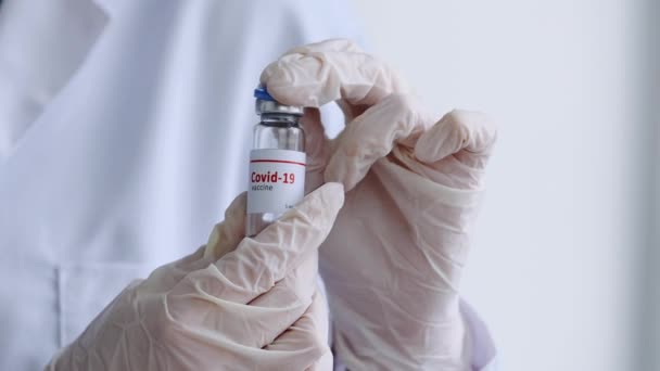Detailní záběr ženských rukou zdravotnického pracovníka držícího lahvičku kovidové 19 vakcíny otevřenou sklenici koronavirového léku tekuté antibiotikum, koncept farmakologie a boj proti kovid-19 chřipce - Záběry, video