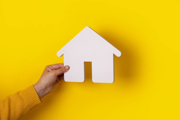 casa in mano su sfondo giallo, concetto di acquisto di una casa a credito - Foto, immagini