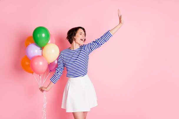 Photo of young attractive excited crazy smiling positive girl hold balloons hold hand say hi isolated on pink color background - Photo, image
