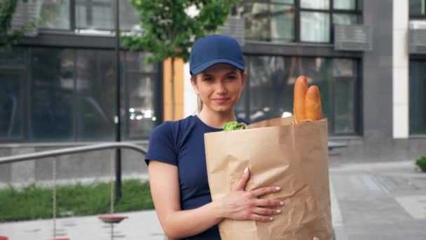 Πορτρέτο χαμογελαστό παράδοση τροφίμων γυναίκα ταχυμεταφορών κατέχει χαρτοσακούλα με παντοπωλεία - Πλάνα, βίντεο
