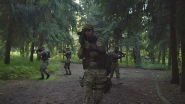 Squad of soldiers moving forward in forest, rifles in firing position - Footage, Video