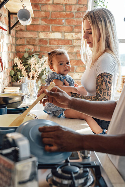 Fröhliches kleines Mädchen mit ihren Eltern beim Kochen in der Küche - Foto, Bild