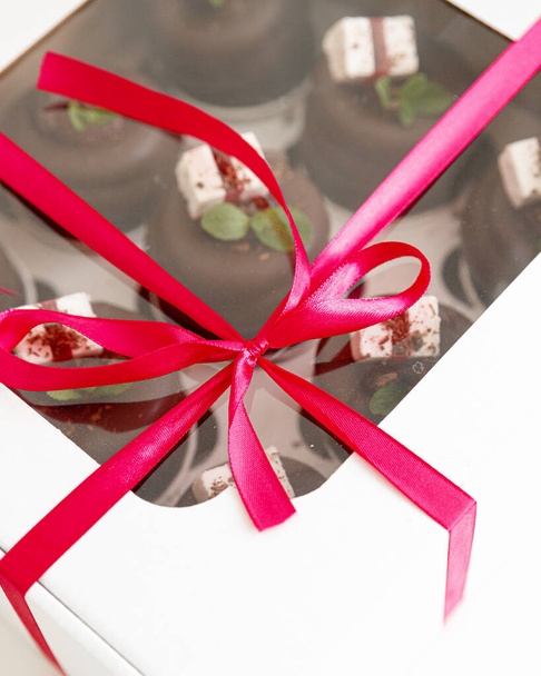 Chocolate cupcakes on top of chocolate decorated with mint and marshmallow with red ribbon - Photo, Image