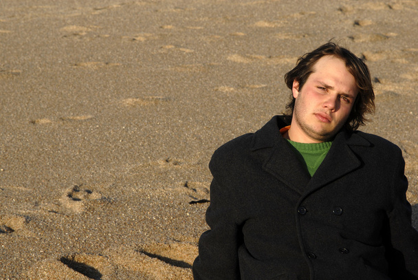 Jeune homme à la plage assis dans le sable
 - Photo, image