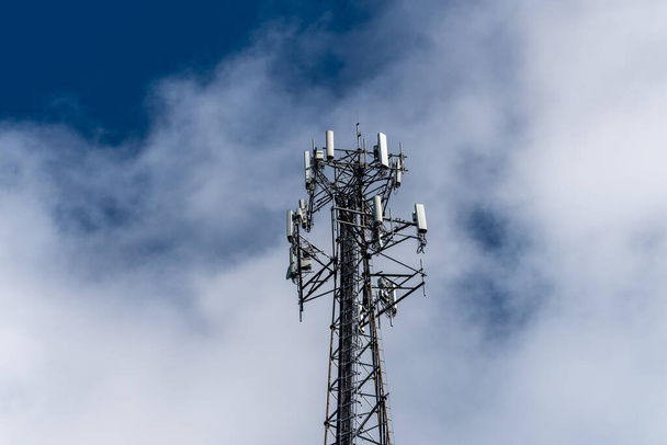 Сотовый телефон или вышка мобильной связи, предоставляющая широкополосный интернет против голубого неба - Фото, изображение