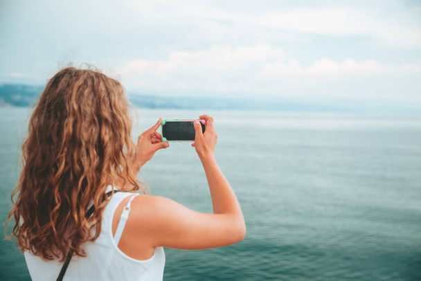 Frau fotografiert das Meer am Telefon Kopierraum - Foto, Bild