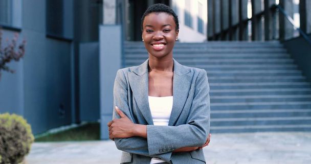 Being successful. Portrait of pleasant happy young multiracial businesswoman is looking at tje camera with joy while standing near the office - Fotó, kép