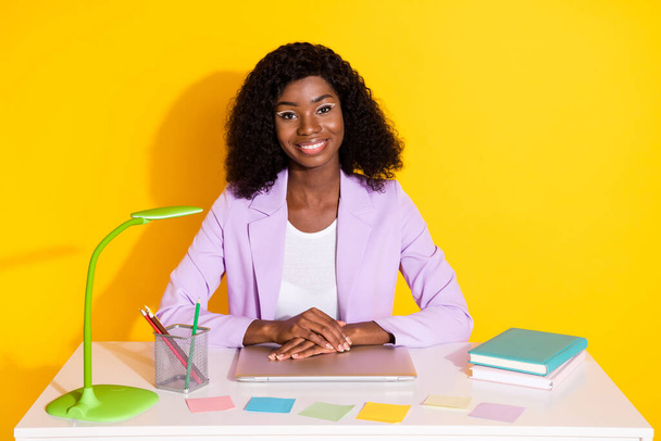 Photo of young happy cheerful smiling representative afro businesswoman sit table isolated on yellow color background - Foto, immagini