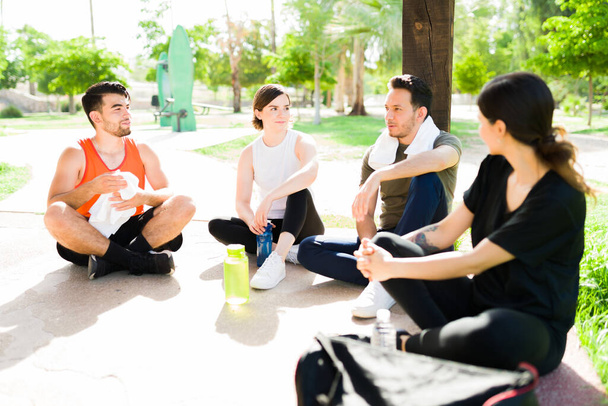 Jóképű spanyol férfi beszél a barátaival, miközben szünetet tart és pihen, mielőtt elkezdene együtt edzeni a parkban. - Fotó, kép