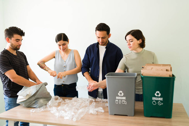 Ympäristöystävällistä toimintaa. Ryhmä nuoria naisia ja miehiä murskaus muovipulloja laittaa roskakoriin  - Valokuva, kuva