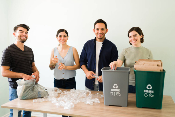 Portrét atraktivních mladých přátel, kteří se usmívají a dívají se do kamery při recyklaci plastových a lepenkových krabic - Fotografie, Obrázek