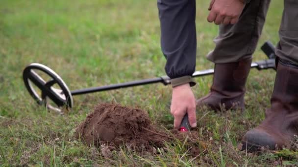 Mann in Stiefeln auf Schatzsuche mit Metalldetektor im Gras. Nahaufnahme eines Mannes, der im Boden nach Münzen sucht  - Filmmaterial, Video