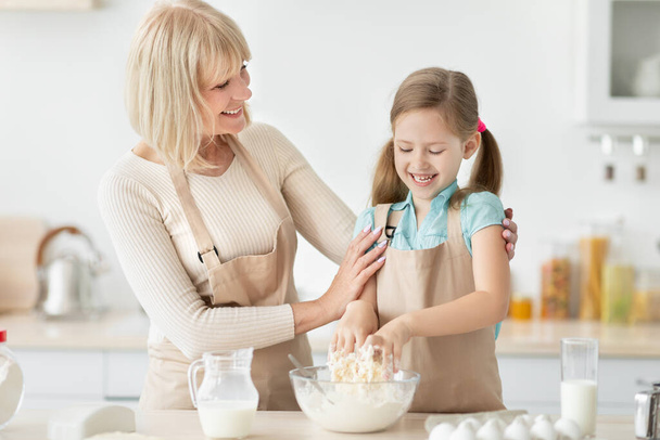 Szczęśliwa seniorka i jej wnuczka przygotowują ciasto - Zdjęcie, obraz