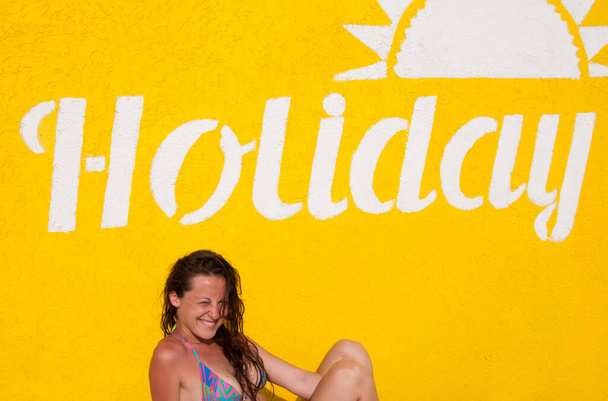 nyári vakáció és nyaralás. ünnepi szöveg a sárga falon. szexi lány nedves hajjal. Fürdőruhás hölgy. nyári üdülőhely medencés strandon. Lazíts és napozz. boldog nő sárga háttér. - Fotó, kép