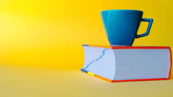 boek en kopje koffie geïsoleerde gele achtergrond - Foto, afbeelding