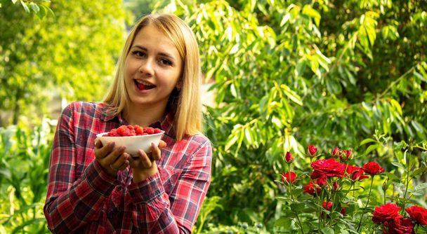 fille tenant un bol avec des produits biologiques de framboises mûres sur la ferme. Concentration sélective - Photo, image