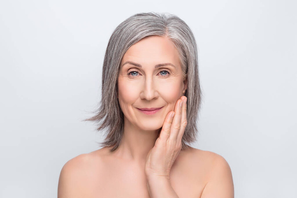 Photo of lovely charming attractive old woman hold hands touch face skin treatment isolated on grey color background - 写真・画像