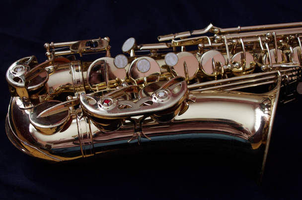 Nahaufnahme eines goldenen Saxophons auf schwarzem Hintergrund  - Foto, Bild