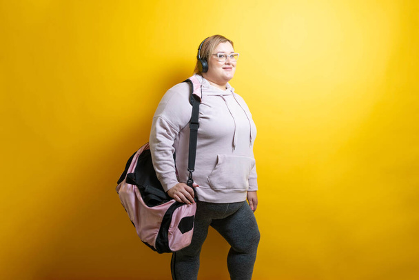 Caucasian Overweight model with sportswear, gym suitcase and headphones. workout - Fotó, kép