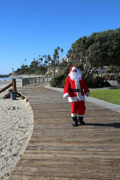 Χριστούγεννα. Άγιε Βασίλη. Διακοπές. Διακοπές στην παραλία. Ο Άγιος Βασίλης είναι σε διακοπές. Ο Άγιος Βασίλης απολαμβάνει μια μέρα στην παραλία. Ο Άγιος Βασίλης περπατά στην παραλία. Άγιος Βασίλης. Σερφάροντας Άγιος Βασίλης. Ο Άγιος Βασίλης πάει για σέρφινγκ. Ο Άγιος Βασίλης απολαμβάνει την παραλία. Καλά Χριστούγεννα..  - Φωτογραφία, εικόνα