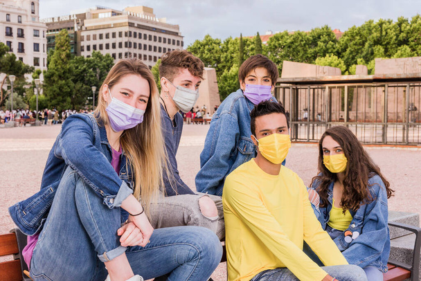 νέα φυσιολογική ζωή του ιού του στέμματος με μια νεαρή μαθητική πολυφυλετική ομάδα που φοράει μάσκα προσώπου για πανδημία - Φωτογραφία, εικόνα