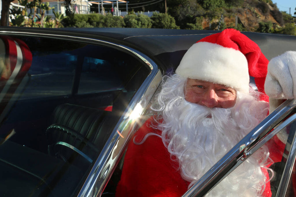 Christmas. Santa Claus. Car. Hot Rod. Red Car. Santa Claus poses for his portrait with his car. Santa Claus gets ready for Christmas. Santa Claus on vacation. Santa Claus Drives his Red Hot Rod Car. Santa Claus in Red Car delivering Christmas Gifts. - Photo, Image