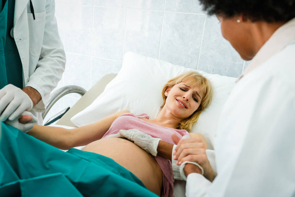 Woman giving birth in hospital with medical doctor team. Healthcare child birth people concept - 写真・画像