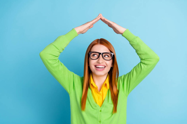 Photo of funny ginger hairdo young lady arms up look up wear spectacles green sweater isolated on blue color background - Fotó, kép