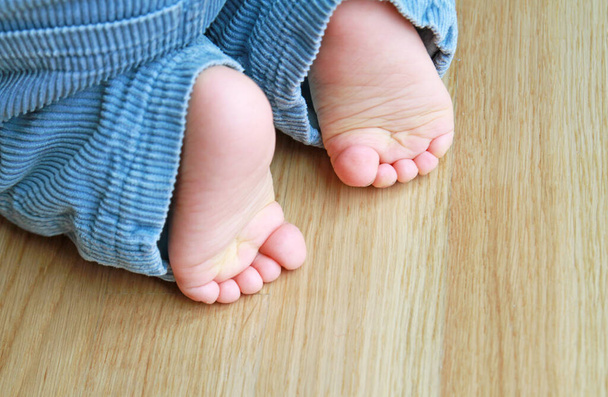 piedi di un bambino piccolo inginocchiato sul parquet - Foto, immagini
