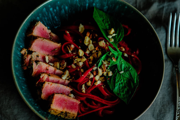 Tuňákový steak s těstovinami z lilku, řepy salátové, lískových oříšků a ricotta omáčkou v modré misce. - Fotografie, Obrázek