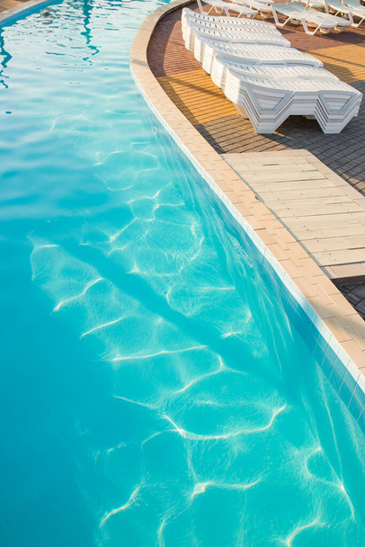 Luxusní lázeňský bazén s salonky ve světle západu slunce, během letní dovolené. - Fotografie, Obrázek