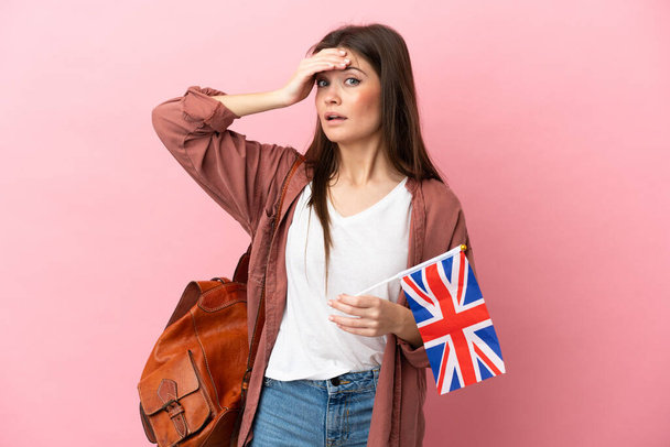 Junge kaukasische Frau mit einer britischen Flagge auf rosa Hintergrund macht Überraschungsgeste, während sie zur Seite schaut - Foto, Bild