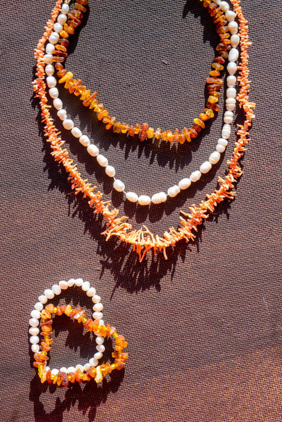  Coral κεχριμπάρι μαργαριτάρι φωτεινά κοσμήματα χάντρες σε σκούρο φόντο. Κολιέ από χάντρες. Κολιέ κόσμημα μοντέρνο σχέδιο μόδας ή υφή. Χώρος για κείμενο. Υψηλής ποιότητας φωτογραφία - Φωτογραφία, εικόνα