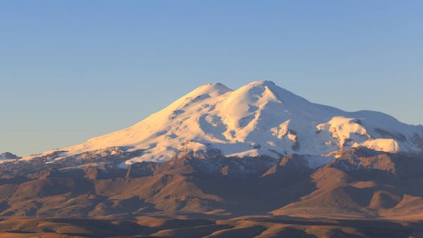 Elbrus w bezchmurny poranek w różowym świetle wschodzącego słońca. Widok z płaskowyżu Bermamyt, Karaczay-Cherkess, Rosja - Zdjęcie, obraz