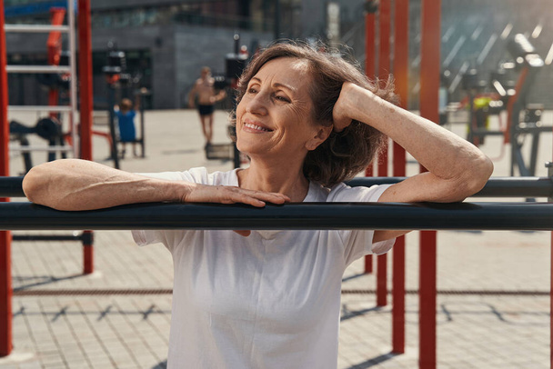 Ευτυχισμένη ηλικιωμένη γυναίκα που κάνει γυμναστική σε ανοιχτό χώρο - Φωτογραφία, εικόνα