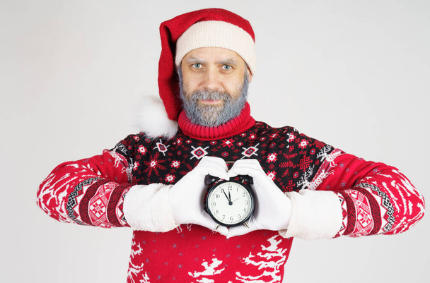 Holiday and Christmas concept. Santa Claus holds a watch in his hands. The palms are folded in the form of a heart - Fotoğraf, Görsel