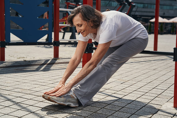Glückliche reife Frau beim Training auf Sportplatz - Foto, Bild