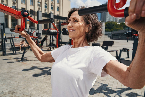 Fröhliche ältere Frau macht kraftvolles Workout im Freien - Foto, Bild