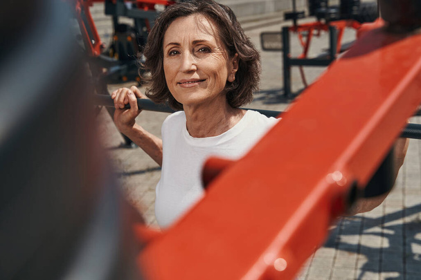 Smiling mature woman working out on sports ground - Foto, imagen