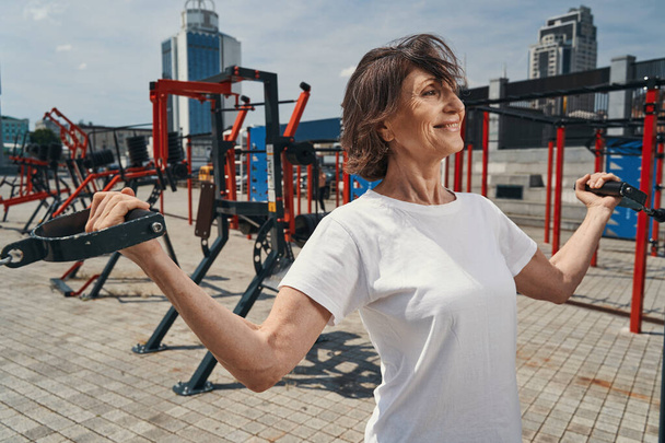 Happy mature female enjoying workout on sports ground - Photo, image