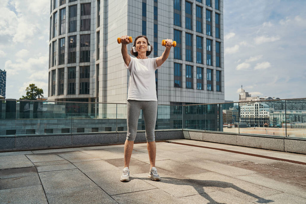 Boldog aktív hölgy csinál edzés a városi tetőn - Fotó, kép